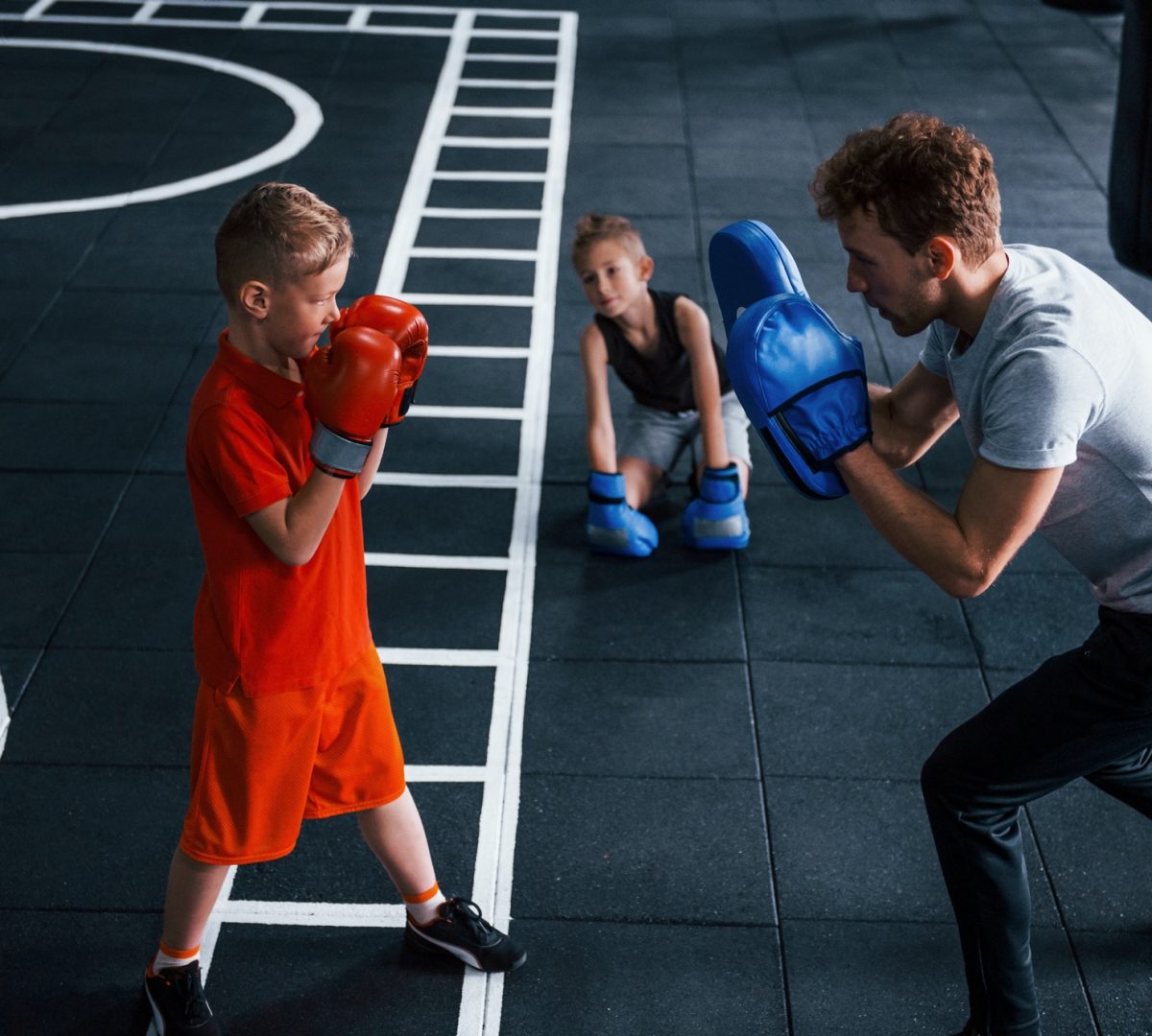 young-trainer-teaches-kids-boxing-sport-in-the-gym.jpg